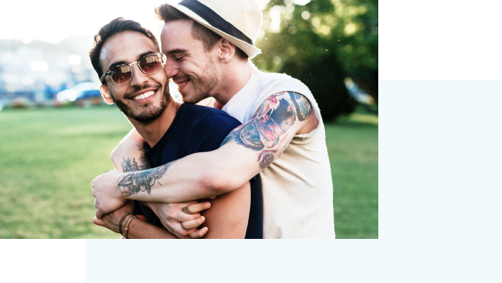 Two smiling men embracing in a park